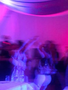 blurry image of people dancing in a room with red and blue lights on the walls