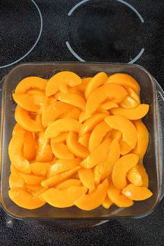 a glass dish filled with sliced mangos on top of a stove