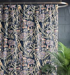 a shower curtain with an abstract design on it next to a potted palm tree