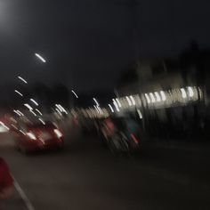 blurry photograph of cars driving down the road at night time with street lights in the background