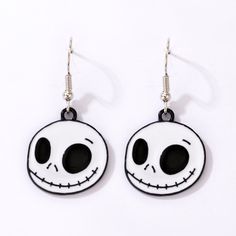 jack skellingy face earrings with black and white enamel on the front, hanging from silver earwires