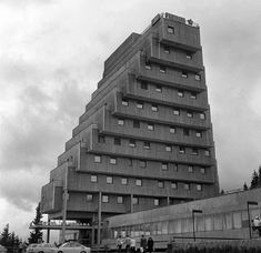 a tall building sitting on the side of a road next to a parking lot with cars parked in front of it