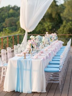 a long table with blue chairs and white linens