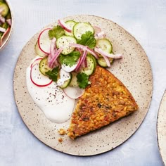 two plates with food on them sitting next to bowls of vegetables and sauces,