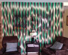 a living room with two couches and green striped curtains on the wall behind them