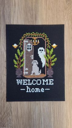 a welcome home cross stitched onto a wooden surface