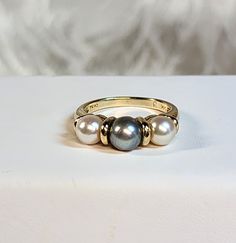 This is a unique and feminine one-of-a-kind ring showcasing 3 beautiful round akoya pearls. There are 2 creamy white 5.5mm round beauties flanking the lustrous silver grey 6.5mm round center pearl.  The setting symbolizes Yesterday, Today and Tomorrow - extremely romantic!  These lovely, iridescent naturally colored organic gems are bar set as well as peg set, for extra security - plus I love the design! The setting is a highly polished, solid 14kt Yellow gold ring setting. It truly is breathtaking, especially since the color of the setting compliments the color of this gemstones. The ring's beautiful colors can be worn year around and they complement every skin tone.  It is not hard to see - the fine coloring is apparent.  And the smallest amount of light captures and transmits the soft g Three Stone Pearl Ring For Anniversary, Anniversary Pearl Ring With Three Stones, Classic Three Stone Pearl Ring, Infinity Ring, Gold Ring Sets, Yellow Gold Setting, Ring Setting, Akoya Pearls, Bar Set