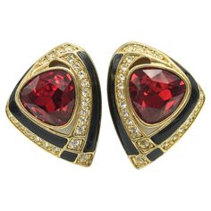 Large 1980s gold tone clip on earrings featuring a black enamel ribbon with a large red rhinestone in the center and white prong set rhinestones ribbon as well. Signed Craft for Gem Craft. Gem Crafts, David Webb, 1980s Fashion, Red Rhinestone, Gold Enamel, Black Enamel, Clip On, Prong Setting, Class Ring