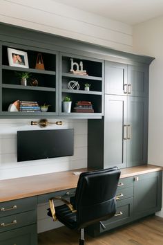 an office with built in cabinets and a computer on the desk, along with a black leather chair