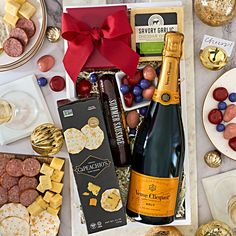 a bottle of champagne, crackers and cheeses on a table with other snacks