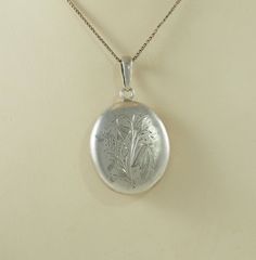 A delightful and large size antique Victorian period silver oval locket back pendant. The front with a brushed finish is charmingly hand chased with a group of meadow flowers and grasses. The reverse with a hinged glazed panel with a beveled edge, for a lock of hair or memento. The reverse of the engraving can be seen within. With a large oval bail for a velvet ribbon. Unmarked. Acid tested as at least 800 standard silver. The chain is for display only. Germany 1880s. 8.7g The opening panel 2.8c Antique Silver Victorian Locket Necklace, Antique Engraved White Gold Locket Necklace, Antique Oval Pendant Locket Necklace For Wedding, Antique Oval Locket Necklace For Wedding, Oval Silver Locket Necklace For Vintage Collection, Silver Oval Locket Necklace For Vintage Collection, Antique Silver Etched Locket Necklace, Vintage Oval Engraved Locket Necklace, Antique White Gold Locket Necklace