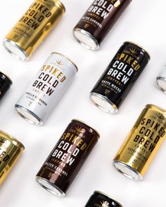 six cans of cold brew are lined up on a white surface with gold and black tins