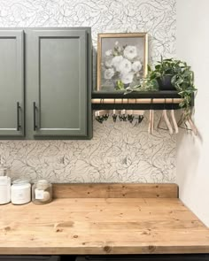 a kitchen with green cabinets and wooden counter tops in front of a wallpapered wall