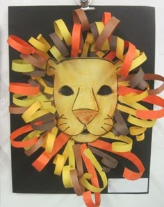 a lion mask made out of strips of colored paper on a piece of black paper