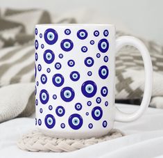 a blue and white coffee mug with an evil eye pattern on it sitting on a bed