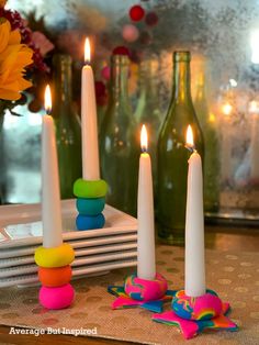 three candles sitting on top of a table next to some bottles and vases with flowers in them