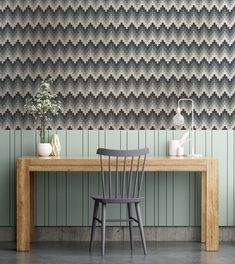 a wooden table and chair in front of a wall with an abstract pattern on it