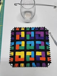 a table topped with a glass filled with water and colorful crochet placemats