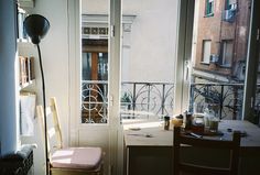 an open door leading to a balcony with a table and chair in front of it