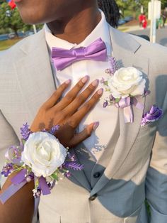 a man in a suit and tie with flowers on his lapel, wearing a purple bow tie