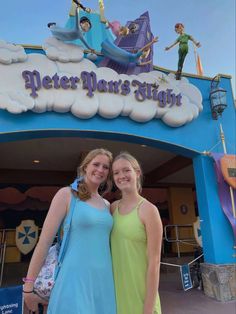 two women standing in front of a sign for peter pan's studio at disney world