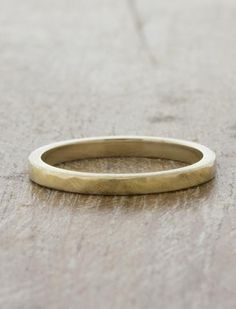 a gold wedding ring sitting on top of a wooden table