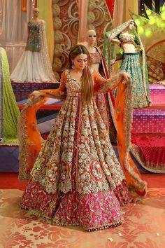 a woman in an orange and pink dress standing next to two mannequins