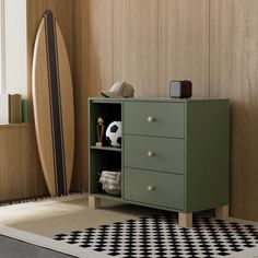 a green cabinet sitting next to a black and white checkered rug with a surfboard in the background