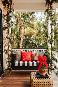 a black and white striped couch on a porch with red bows tied to it's pillows