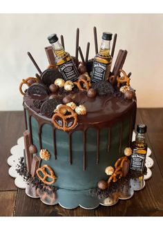 a cake with chocolate frosting and pretzels on top is decorated with an assortment of liquor bottles