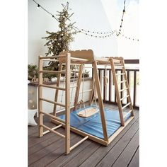 a child's swing set on a deck with christmas lights in the background