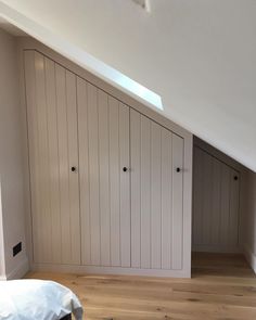 an attic bedroom with white walls and wooden floors, built - in closets on the far wall