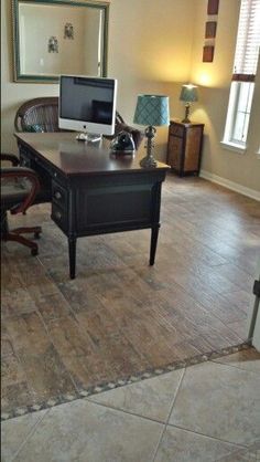 a computer desk sitting on top of a hard wood floor next to a chair and lamp