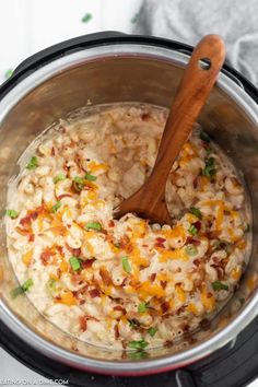 the rice is being cooked in the crock pot with a wooden spoon on top