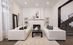 a living room with two white couches and a fireplace in the middle of it