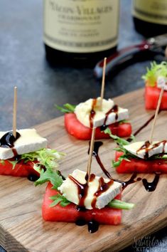 watermelon and cheese appetizers on a cutting board with wine in the background