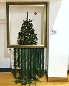 a christmas tree made out of branches in front of a framed photo on the floor