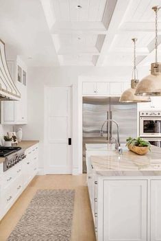 a large kitchen with white cabinets and marble counter tops, along with stainless steel appliances