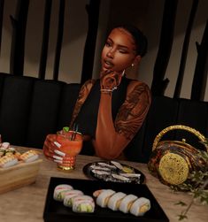 a woman sitting at a table with sushi and drinks