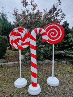 two giant candy canes sitting on top of each other in front of some bushes