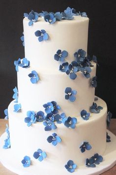 a three tiered cake with blue flowers on it