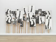 an art work with multiple pieces of artwork on wooden sticks in front of a white wall