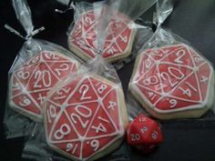 some cookies with white icing and red dices in plastic wrappers on a table