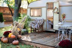 an rv is parked in the yard with pumpkins and other decorations on the deck