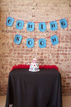 a table with a cake and bunting banner on the wall behind it that says coming soon