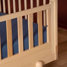 a wooden crib with blue sheets on it