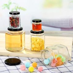 three jars filled with candy sitting on top of a wooden cutting board next to some candies