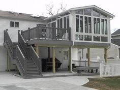 a two story house with stairs leading up to the second floor and an attached deck