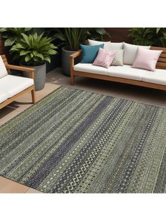 an outdoor area rug with two couches and some plants in the backround