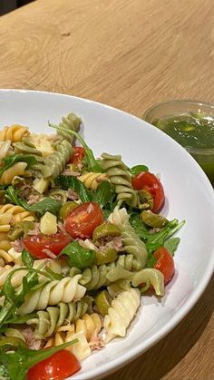 a white plate topped with pasta salad next to a glass of green smoothie juice